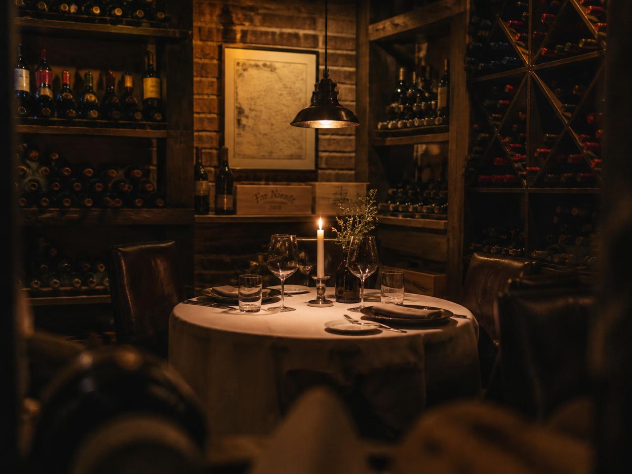 Secluded wine-cellar dining nook set for a small private dinner